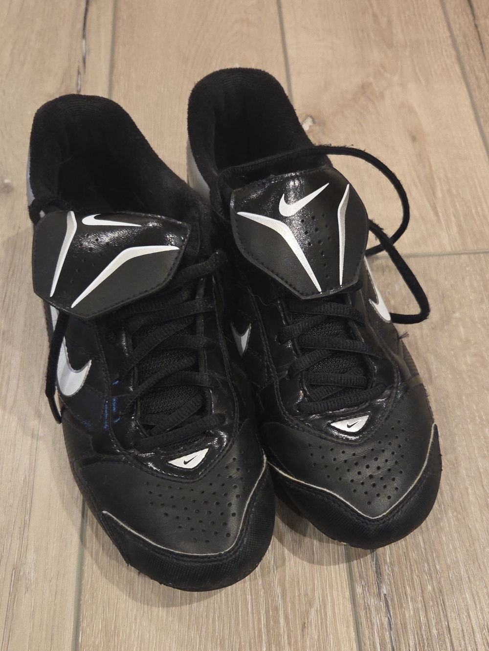 Nike low-top baseball cleats featuring a distinctive lace-cover flap over the fo
